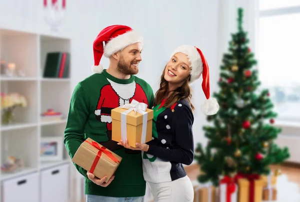 Couple heureux en pull laid avec cadeaux de Noël — Photo