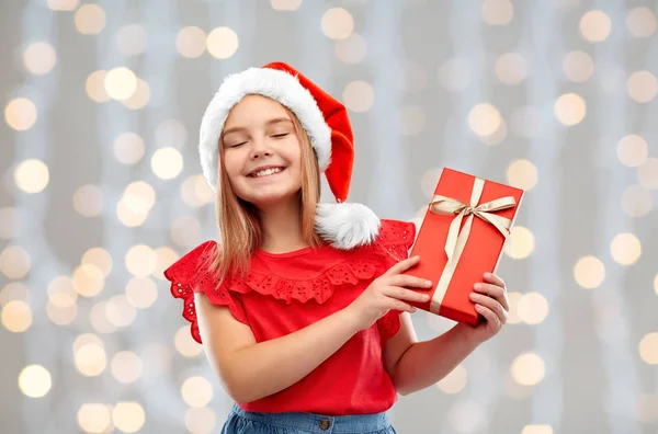 Pleased girl in santa hat with christmas gift — ストック写真