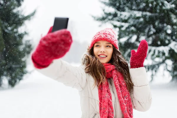 Молодая женщина делает селфи на смартфоне зимой — стоковое фото