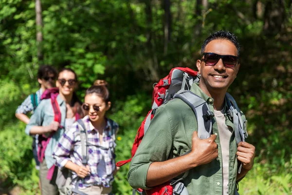 Skupina přátel s batohy turistika v lese — Stock fotografie