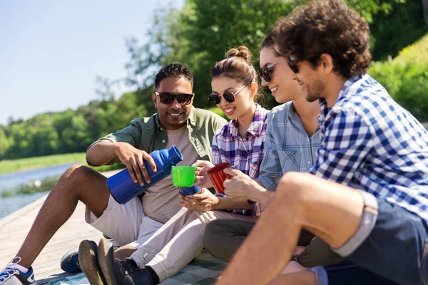 Amici felici bere il tè dal thermos in estate — Foto Stock