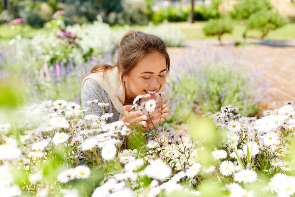 Mulher feliz cheirando flores de camomila no jardim — Fotografia de Stock