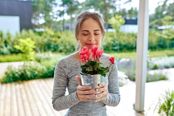 Mujer joven con flores de ciclamen en el jardín de verano — Foto de Stock
