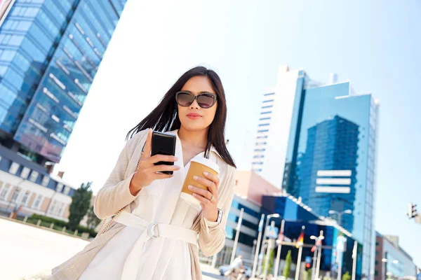 Leende kvinna med smartphone och kaffe i staden — Stockfoto