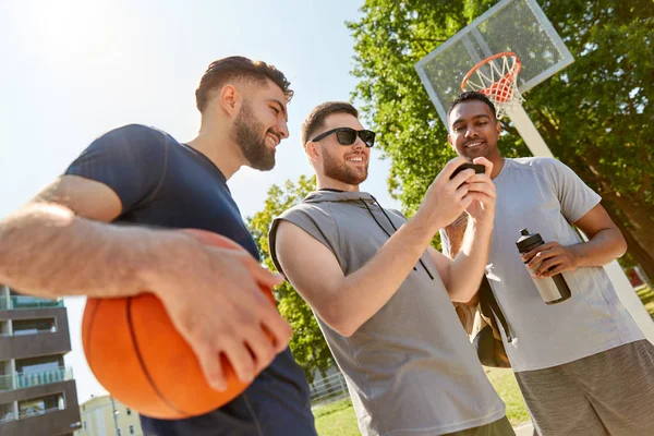 Hommes avec smartphone sur terrain de basket — Photo