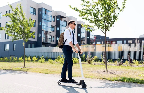 Homem de negócios com mochila montando scooter elétrico — Fotografia de Stock