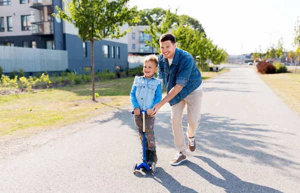 Szczęśliwy ojciec i mały syn jazda skuter w mieście — Zdjęcie stockowe