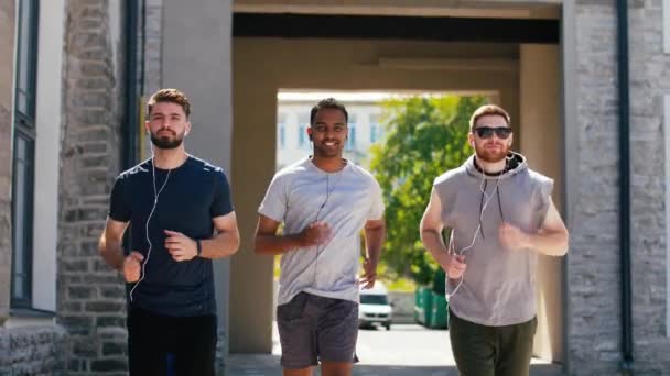 Amis masculins avec écouteurs courir à l'extérieur — Video