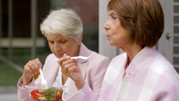 Пожилые женщины едят еду на вынос на городской улице — стоковое видео