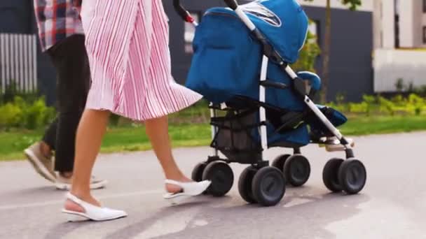Family with baby in stroller walking along city — Stock Video