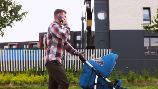 Pappa med barnvagn ringer på smartphone i City — Stockvideo