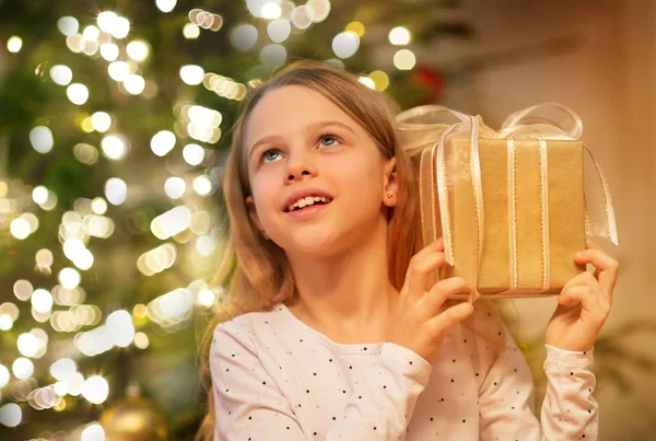 Menina sorridente com presente de Natal em casa — Fotografia de Stock