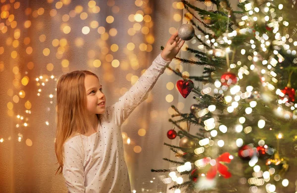 Glückliches Mädchen in rotem Kleid schmückt Weihnachtsbaum — Stockfoto