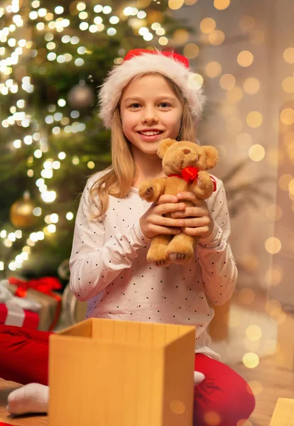 サンタ・ハットの笑顔の女の子とクリスマスプレゼント — ストック写真