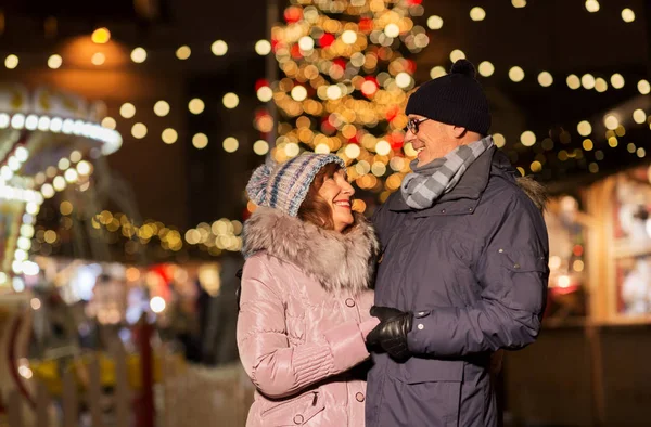 Heureux couple de personnes âgées étreignant au marché de Noël — Photo