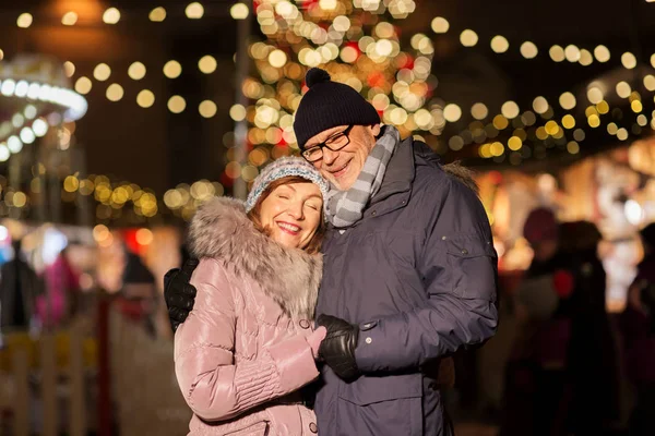 Heureux couple de personnes âgées étreignant au marché de Noël — Photo