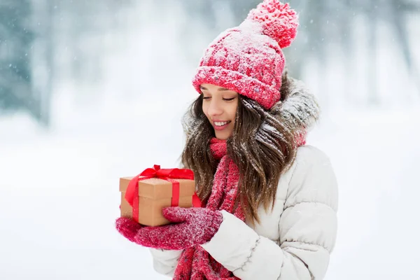 Счастливая молодая женщина с рождественским подарком зимой — стоковое фото