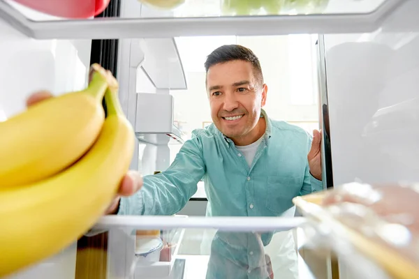 Homme prenant banane du réfrigérateur à la maison cuisine — Photo