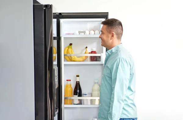 Homme à la recherche de nourriture au réfrigérateur à la cuisine — Photo