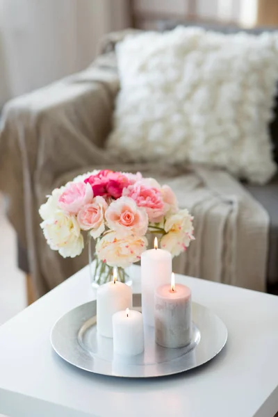 Candles burning on table and flowers at cozy home Stock Image