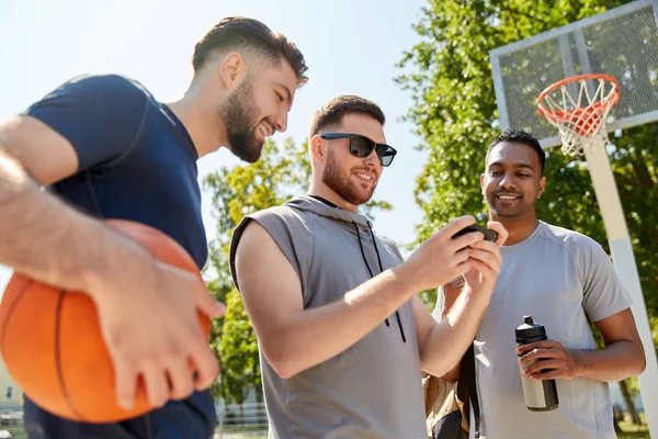 Muži se smartphone na basketbalovém hřišti — Stock fotografie