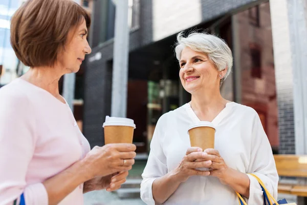 Senior women with shopping bags and coffee in city — Stock Photo, Image