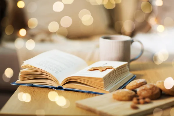 Book with autumn leaf, cookies and tea on table — Stock Photo, Image