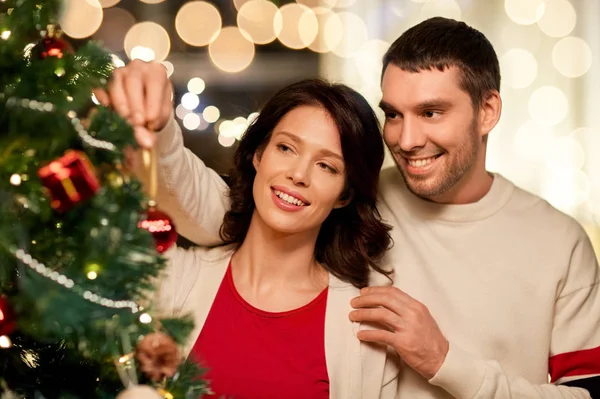 Happy couple decorating christmas tree at home — Stock Photo, Image