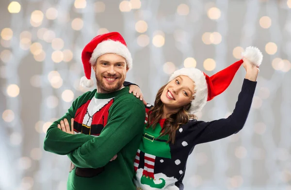 Gelukkig paar in kerst truien en santa hoeden — Stockfoto