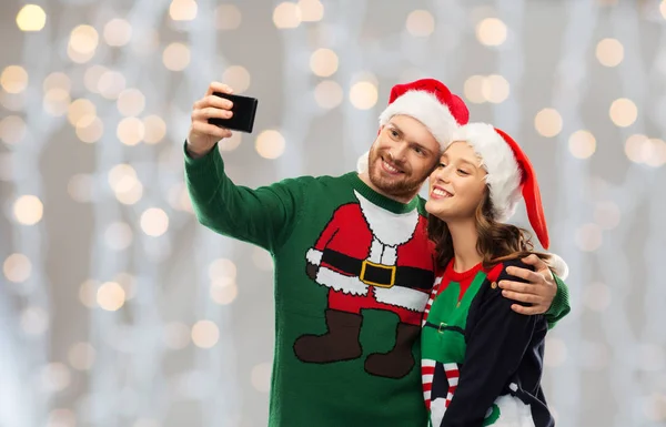 Happy couple in christmas sweaters taking selfie — Stock Photo, Image