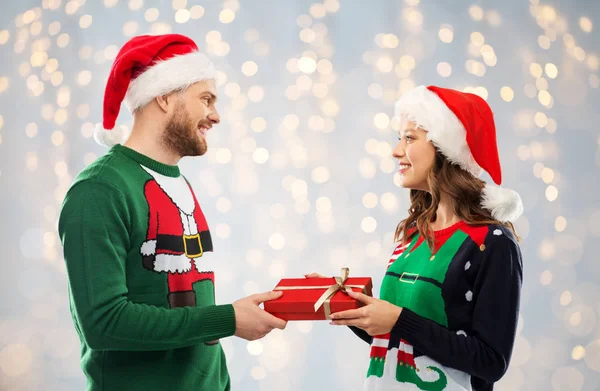 Happy couple in sweaters with christmas gift — Stock Photo, Image