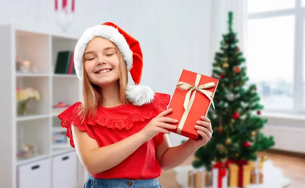 Meisje in Santa hoed met kerstcadeau thuis — Stockfoto