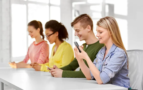 Estudiantes de secundaria feliz con teléfonos inteligentes — Foto de Stock
