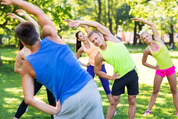 Grupo de personas felices haciendo ejercicio en el parque de verano — Foto de Stock