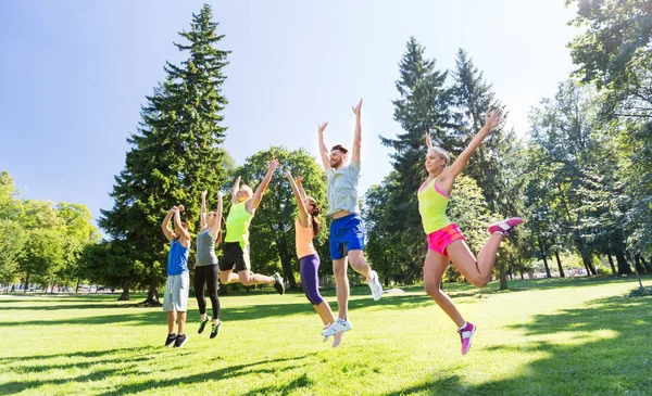 group of happy friends jumping high at park