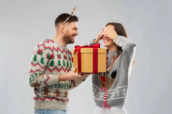 Casal feliz em camisolas de Natal com caixa de presente — Fotografia de Stock