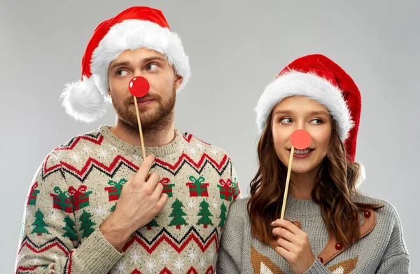 Casal com adereços de festa de Natal em camisolas feias — Fotografia de Stock