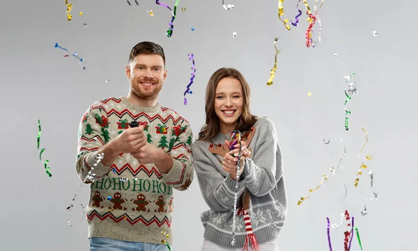 穿着圣诞羊毛衫的情侣们跳着派对的爆米花 — 图库照片