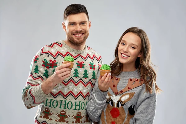 夫妇与杯蛋糕在丑陋的圣诞毛衣 — 图库照片