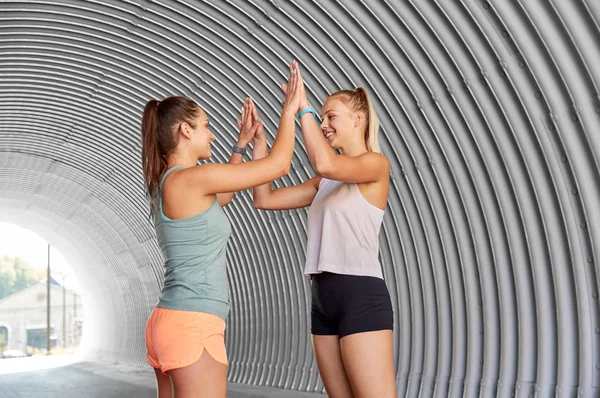 Mulheres felizes com rastreadores de fitness fazendo alta cinco — Fotografia de Stock