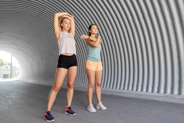 Женщины с фитнес-трекерами растягиваются на открытом воздухе — стоковое фото