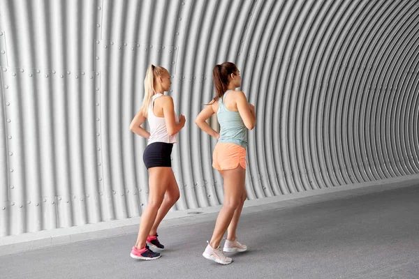 Mujeres jóvenes o amigas corriendo al aire libre — Foto de Stock