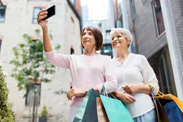 Öregasszonyok bevásárló táskák figyelembe selfie a városban — Stock Fotó