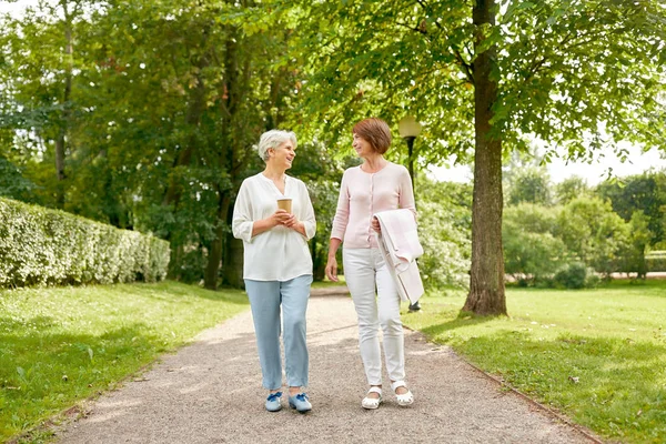 senior women or friends drinking coffee at park