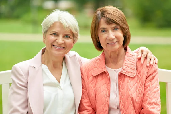 Senior women or friends sitting on bench at park — Stock Photo, Image