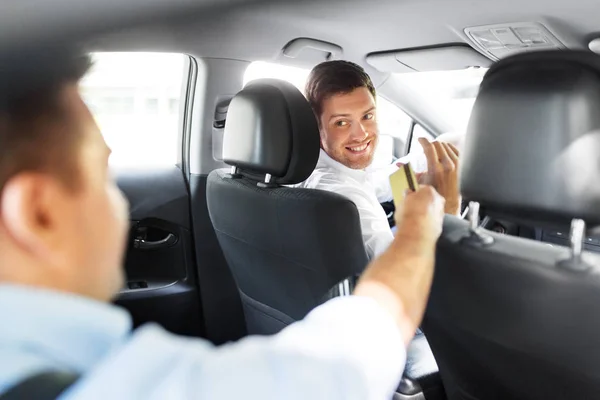 Мужчина водитель автомобиля берет кредитную карту у пассажира — стоковое фото