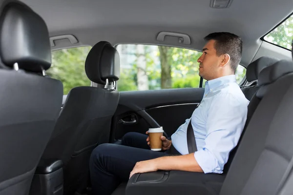 Homem de negócios com takeaway café no banco de trás do carro — Fotografia de Stock