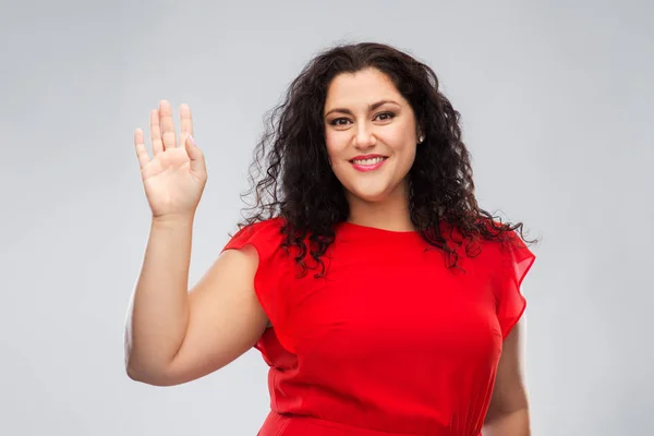 Gelukkig vrouw in rood jurk zwaaien hand — Stockfoto