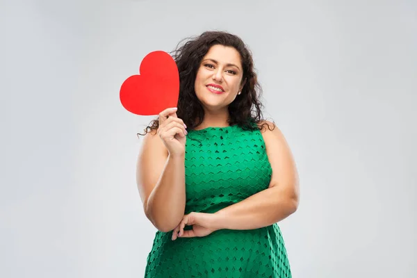 Mujer feliz en vestido verde sosteniendo el corazón rojo — Foto de Stock