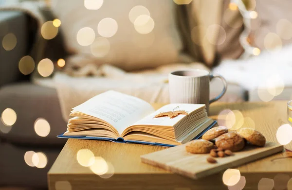 Libro con hojas de otoño, galletas y té en la mesa — Foto de Stock